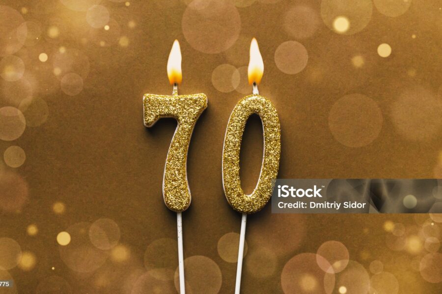 Burning Golden Glitter Number 70 Celebration Candle On Brown Bokeh Background