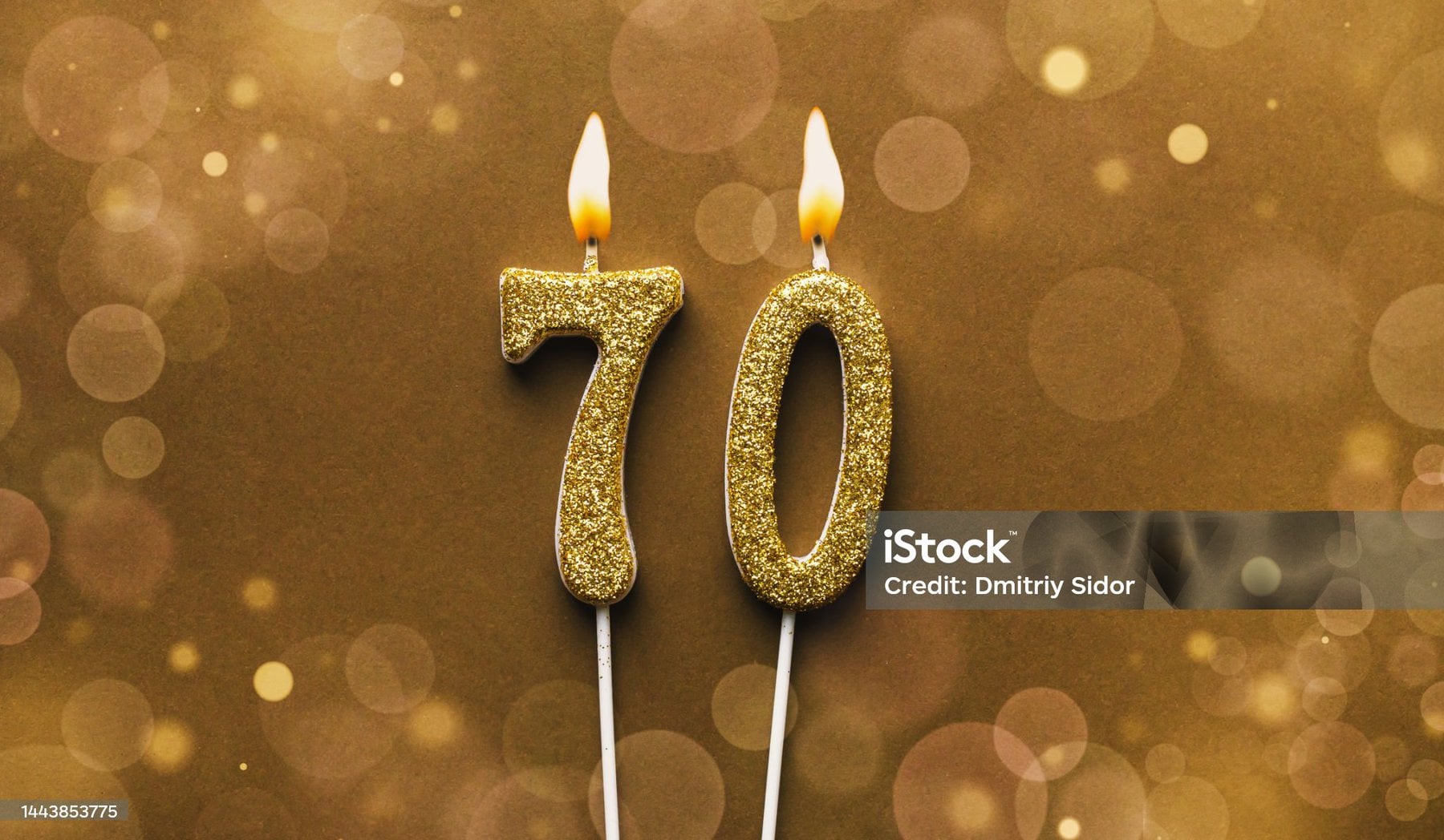 Burning Golden Glitter Number 70 Celebration Candle On Brown Bokeh Background